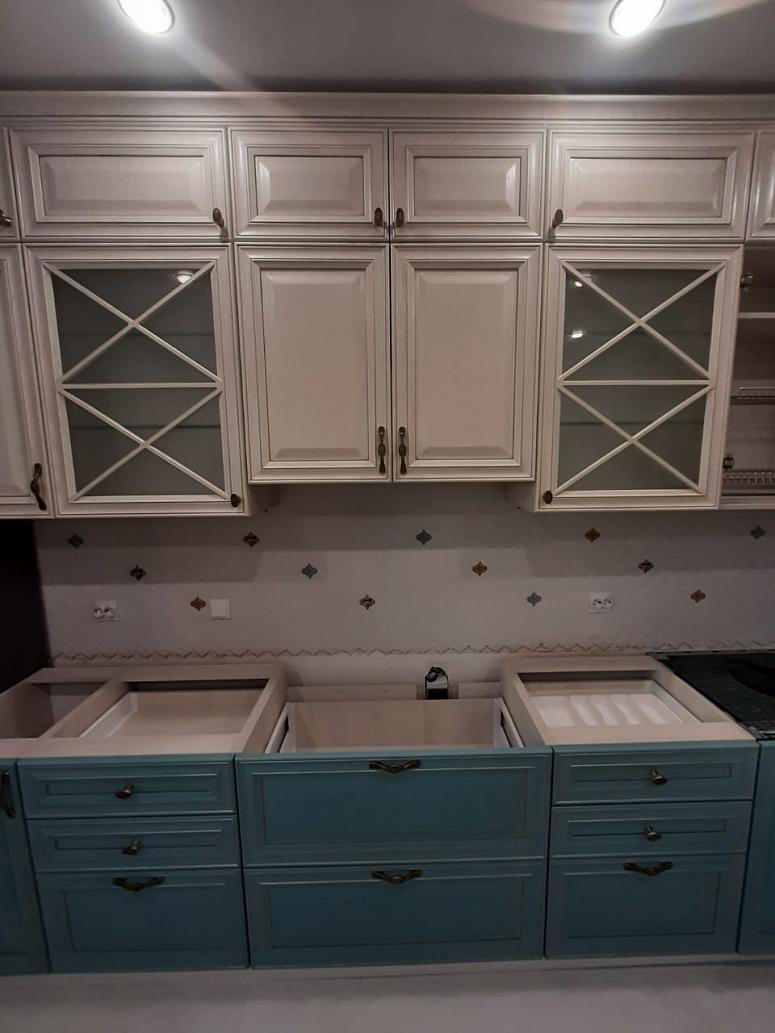 Фото угловая трехъярусная белая двухцветная матовая синяя светлая кухня из массива в неоклассическом стиле c акриловой столешницей