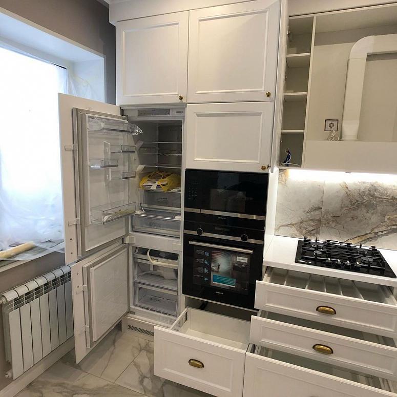 Фото угловая белая кухня с крашеными фасадами в неоклассическом стиле с пластиковой столешницей