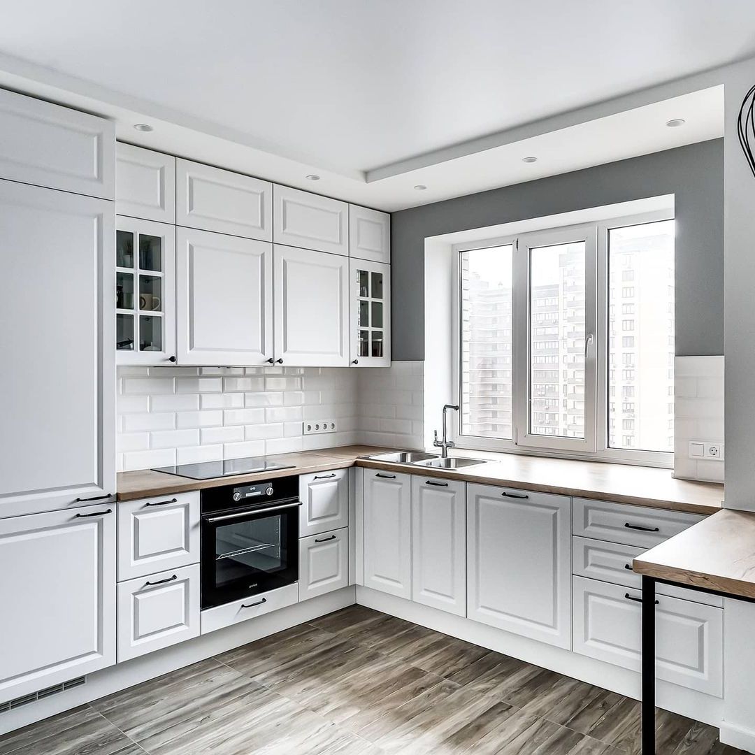 Белая угловая кухня с крашеными фасадами в неоклассическом стиле с пластиковой столешницей
