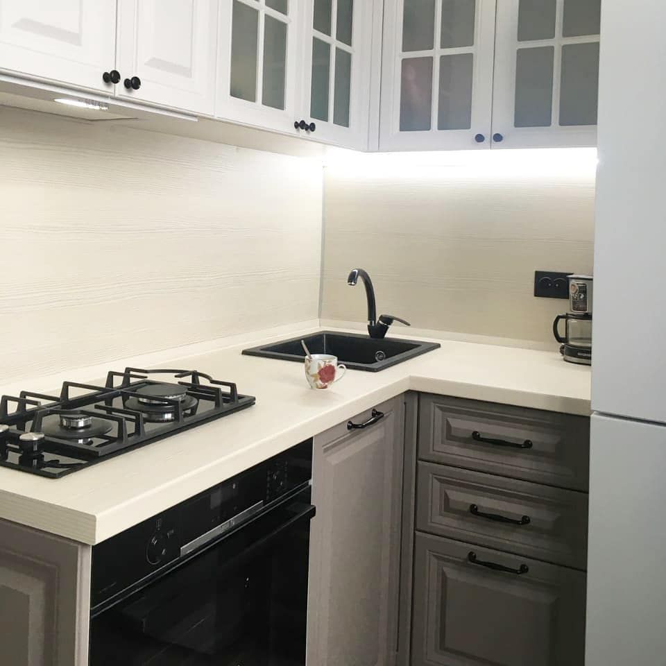 Белая угловая кухня с крашеными фасадами в неоклассическом стиле с кварцевой столешницей