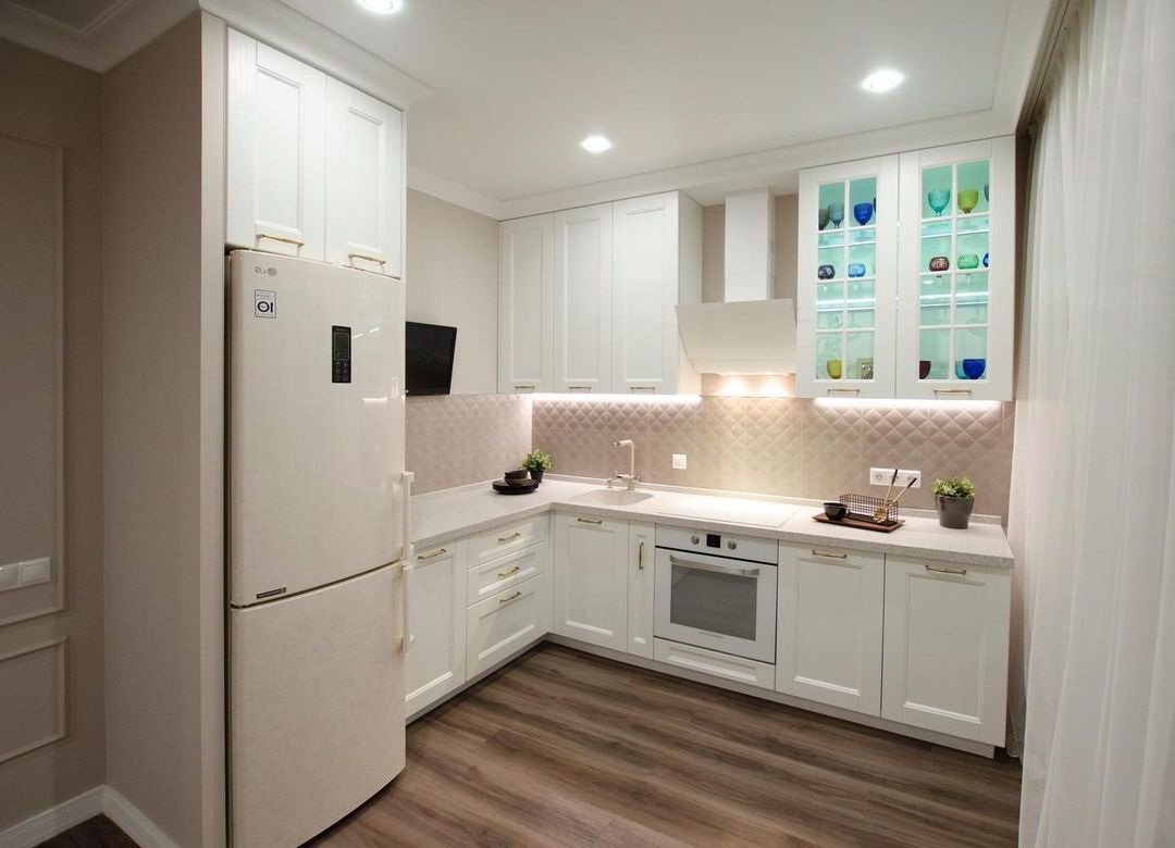 Белая угловая кухня с крашеными фасадами в неоклассическом стиле с кварцевой столешницей