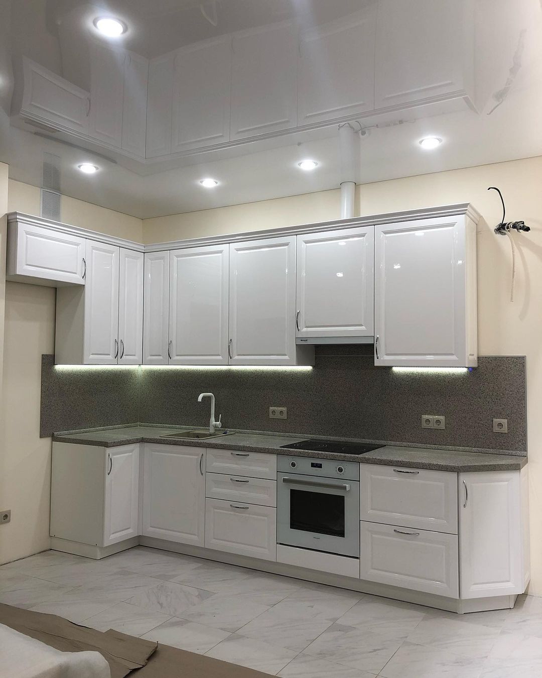 Белая угловая кухня с крашеными фасадами в неоклассическом стиле с пластиковой столешницей