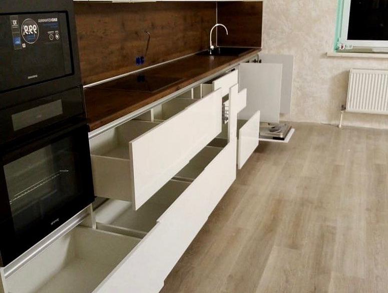 Фото прямая белая древесная кухня с пластиковыми фасадами в стиле Хай-Тек и в стиле Минимализм с пластиковой столешницей