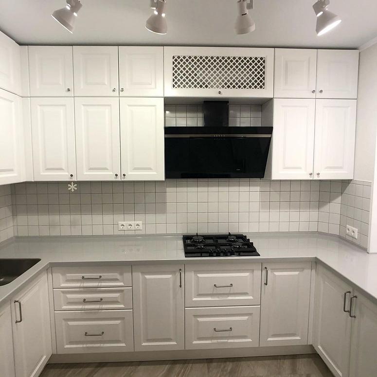 Фото п-образная белая светлая кухня с крашеными фасадами в неоклассическом стиле c акриловой столешницей