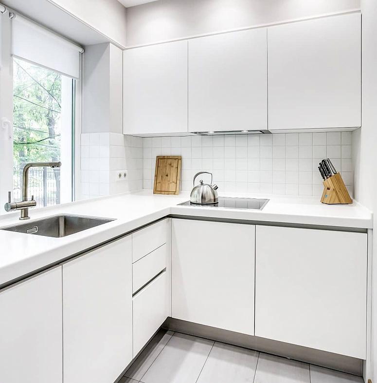 Фото угловая белая глянцевая светлая кухня с пластиковыми фасадами в стиле Хай-Тек и в стиле Минимализм c акриловой столешницей