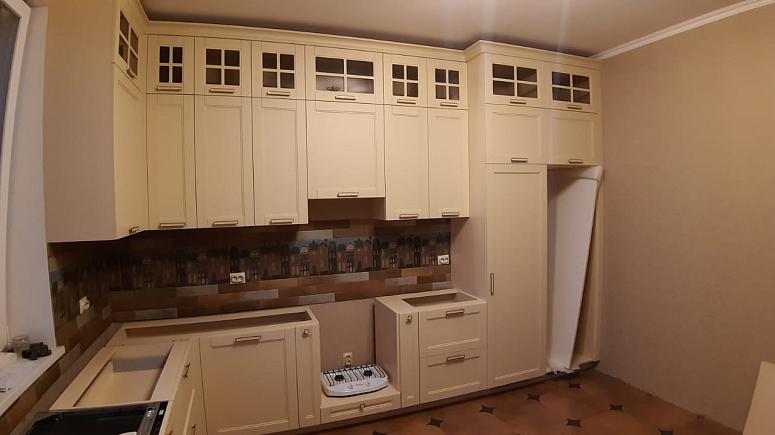 Фото угловая трехъярусная бежевая матовая светлая кухня с крашеными фасадами в неоклассическом стиле c акриловой столешницей