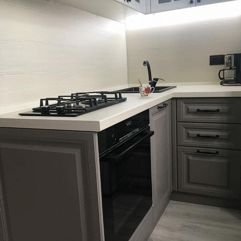 Фото угловая белая двухцветная серая светлая кухня с крашеными фасадами в неоклассическом стиле с кварцевой столешницей