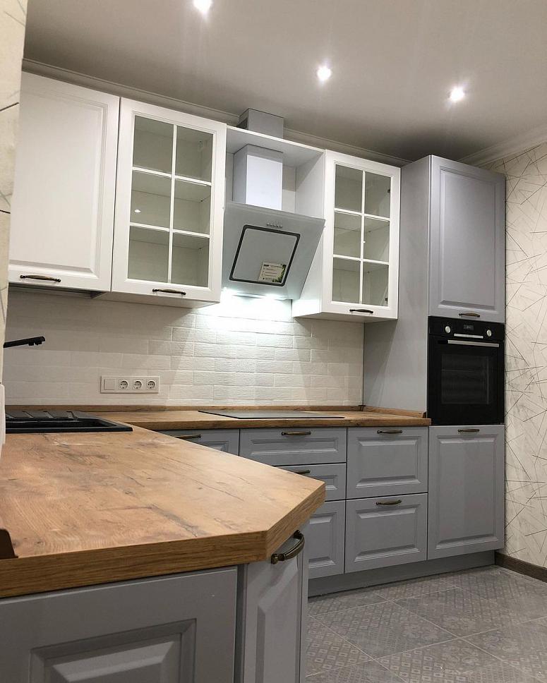 Фото угловая белая древесная двухцветная серая кухня с крашеными фасадами в неоклассическом стиле