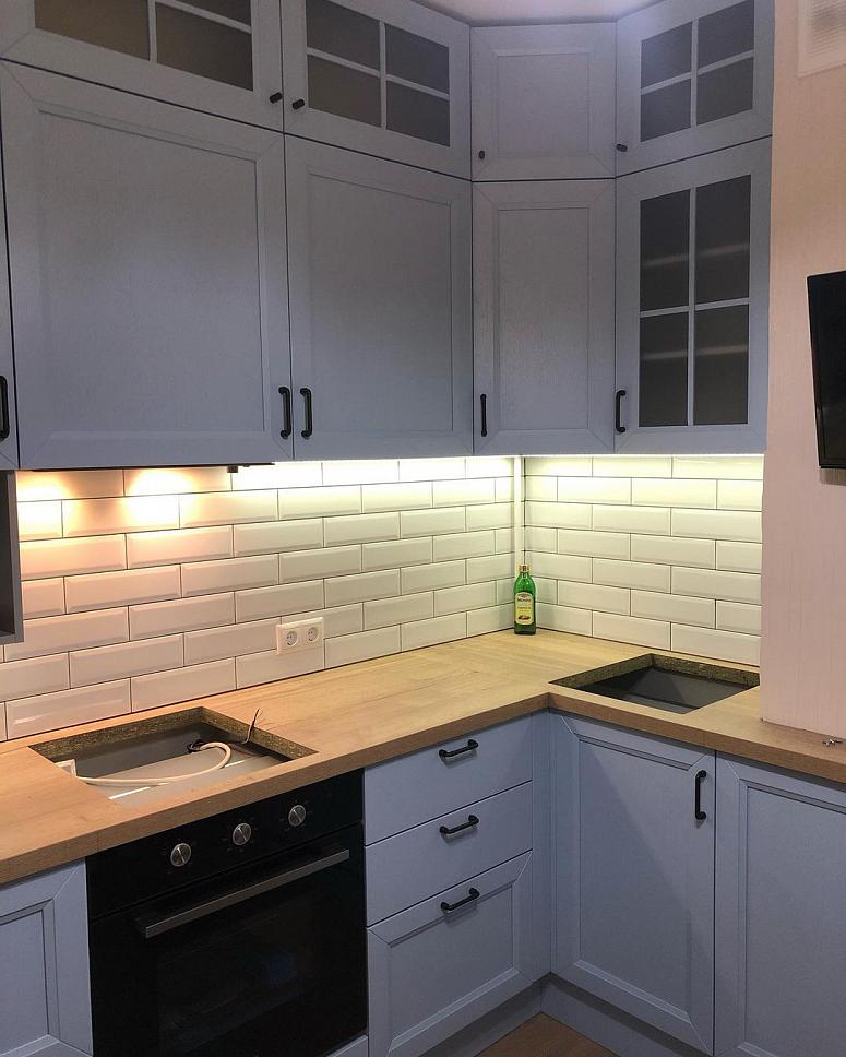 Фото угловая белая древесная матовая светлая кухня с фасадами МДФ-ПВХ в неоклассическом стиле с пластиковой столешницей