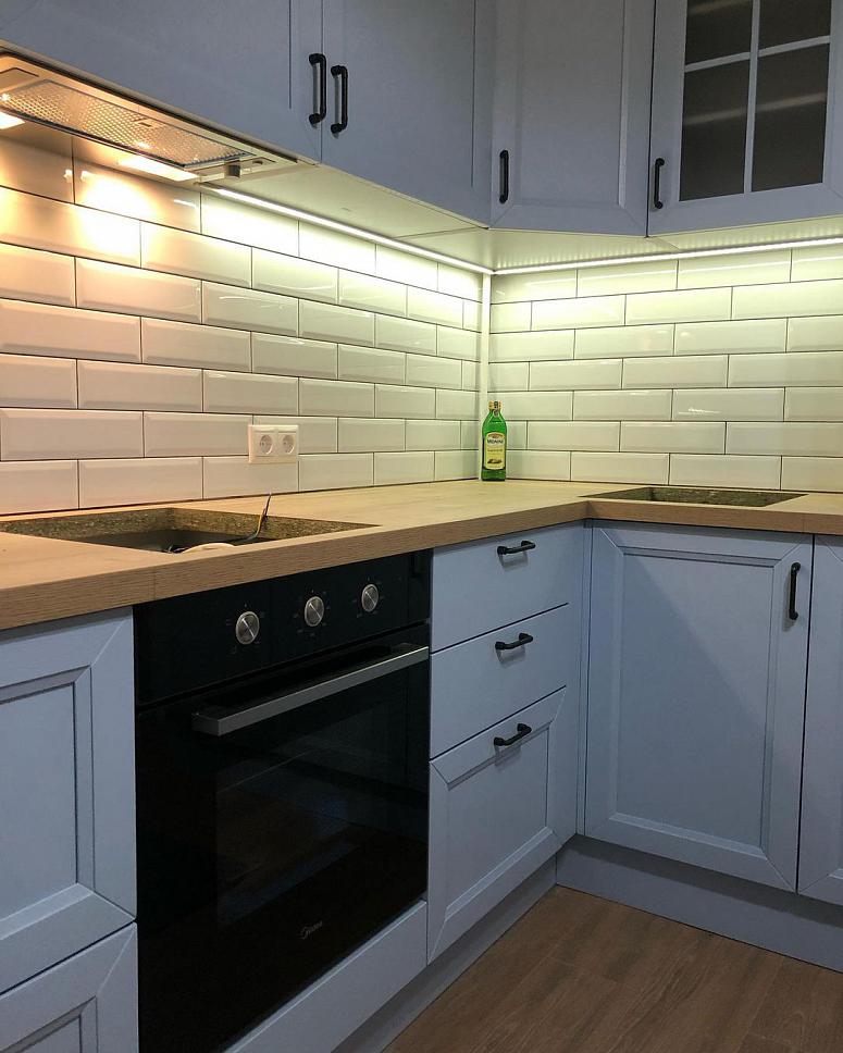 Фото угловая белая древесная матовая светлая кухня с фасадами МДФ-ПВХ в неоклассическом стиле с пластиковой столешницей