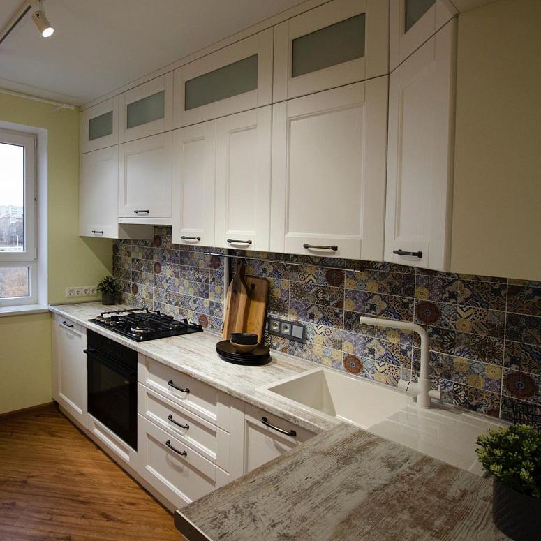 Фото угловая трехъярусная белая светлая древесная кухня с фасадами МДФ-ПВХ в неоклассическом стиле с пластиковой столешницей