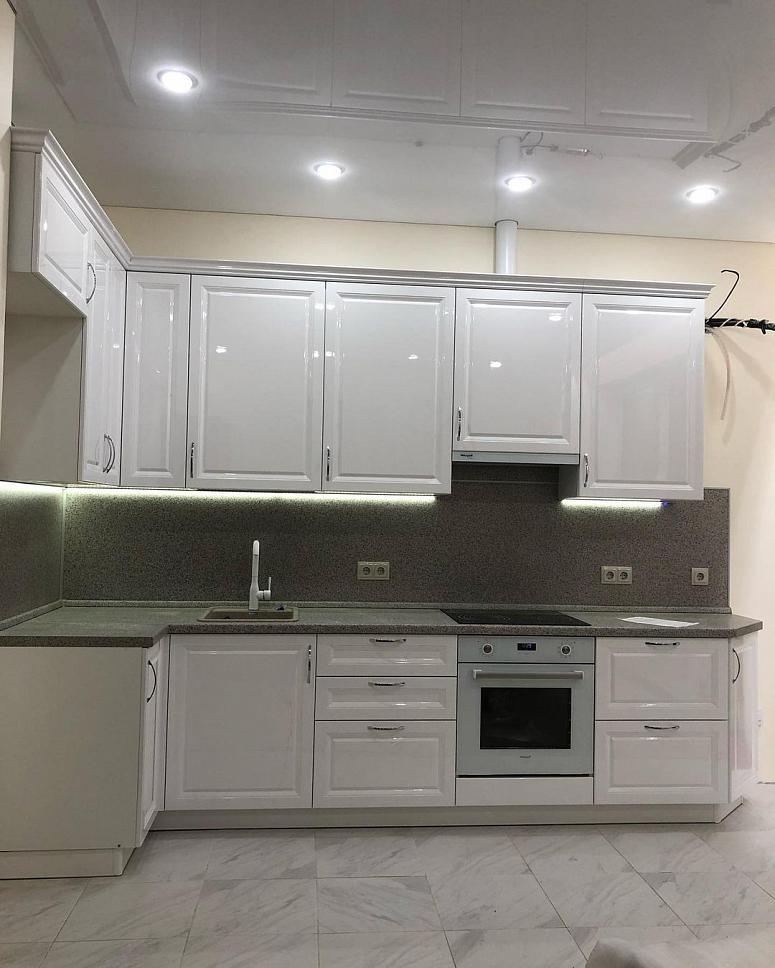 Фото угловая белая глянцевая светлая кухня с крашеными фасадами в неоклассическом стиле с пластиковой столешницей