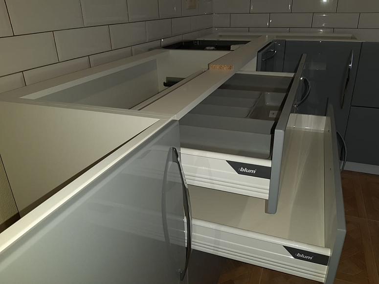 Фото угловая п-образная белая двухцветная матовая серая светлая кухня с фасадами МДФ-ПВХ в стиле Минимализм c акриловой столешницей